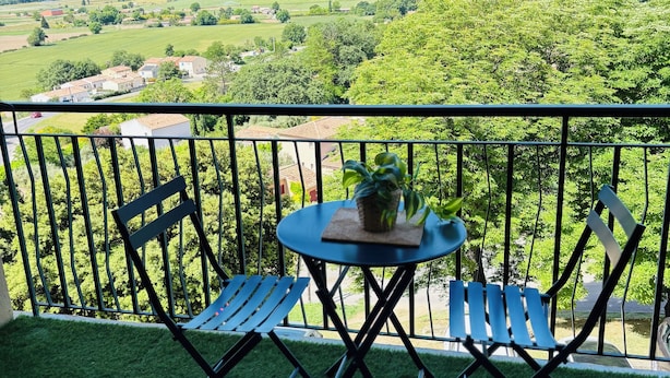 A balcony with a table and two chairs, overlooking a green landscape with trees and buildings. - Studio à Gréoux les Bains - Les Fontaines (Gréoux-les-Bains)