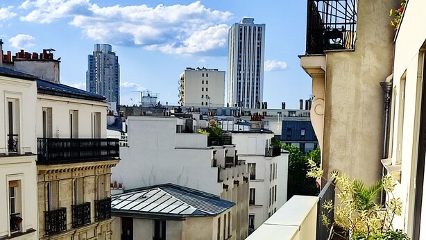 A balcony with potted plants, a view of surrounding buildings, and a clear sky. - Apartment near Parc des Buttes Chaumont - 4 bedrooms (Paris)
