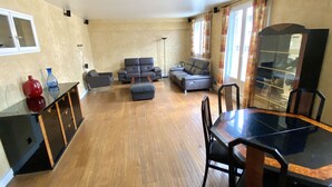 A spacious living room with a wooden floor, a dining table with chairs, and a sofa set. - Apartment near Parc des Buttes Chaumont - 4 bedrooms (Paris)