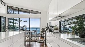Una cocina moderna con vista al océano, ventanas amplias y un comedor con vistas.
