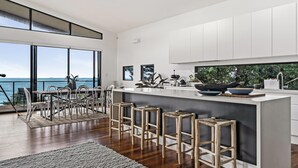 Una cocina moderna con una isla grande, taburetes de bar y vistas al océano.