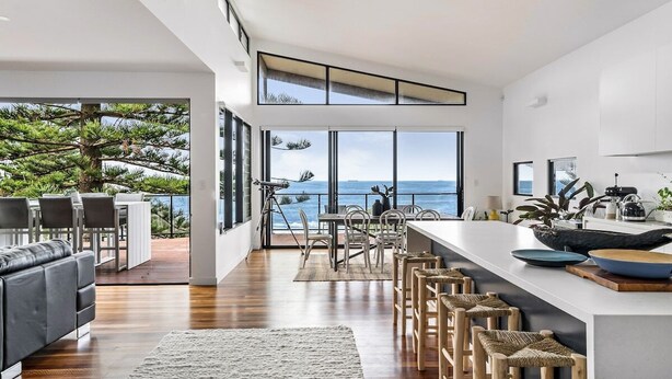 Cocina moderna con una isla grande, comedor y vista al océano.