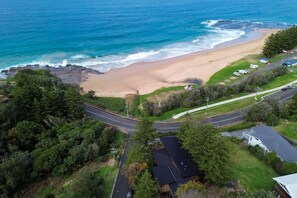 Vista aérea de una zona costera con playa, carretera y propiedades residenciales.