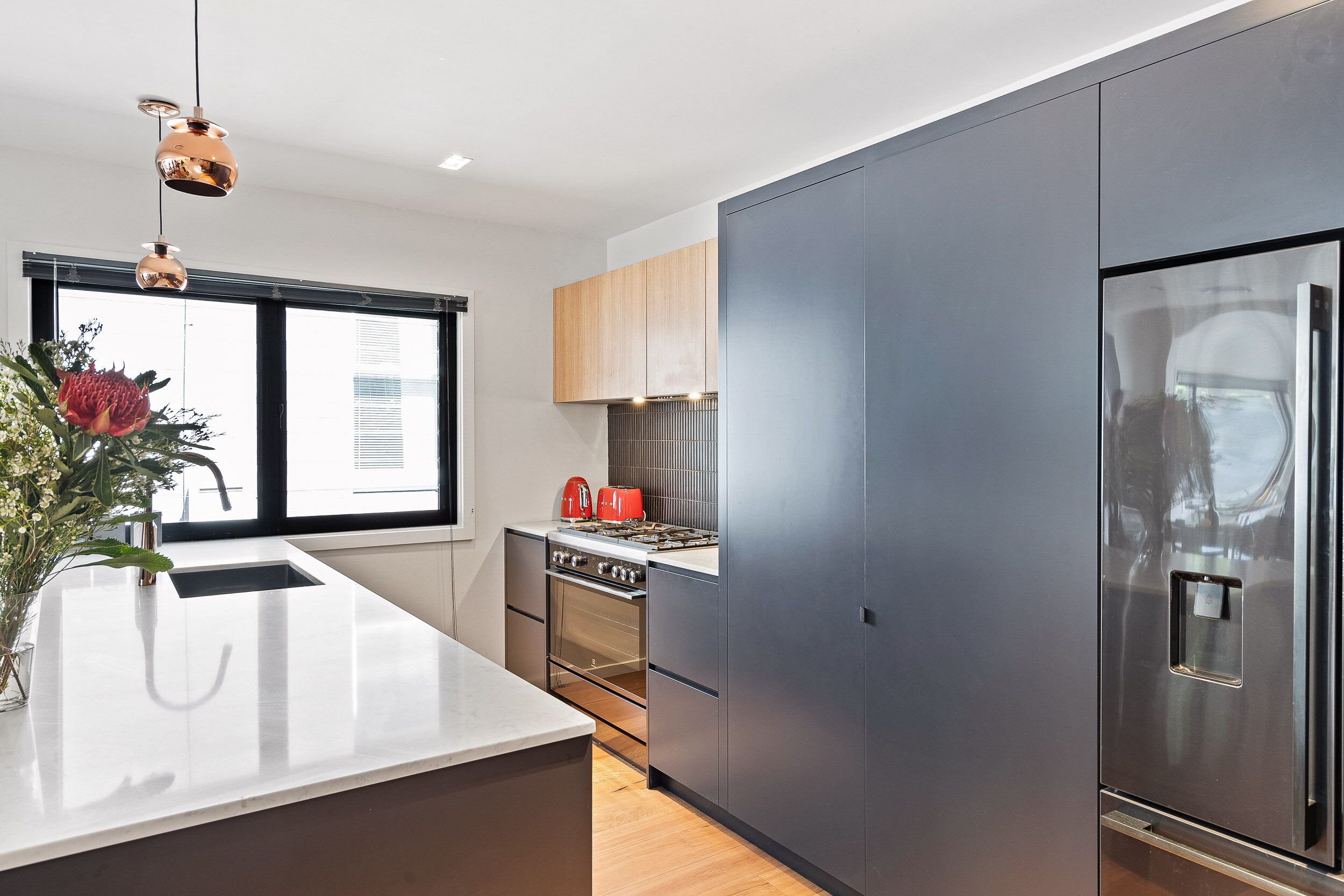 Una cocina moderna con una isla grande, electrodomésticos de acero inoxidable y vistas de la ciudad a través de amplios ventanales.