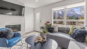 Una sala de estar moderna con chimenea, un ventanal con vistas a la montaña y un sillón azul.