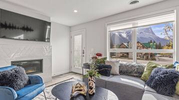 A modern living room with a fireplace, a large window with a mountain view, and a blue armchair.