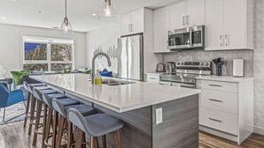Una cocina moderna con una isla grande, electrodomésticos de acero inoxidable y una zona de bar con taburetes.