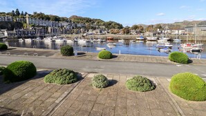 Un port avec des bateaux, une promenade dallée et des bâtiments en arrière-plan.