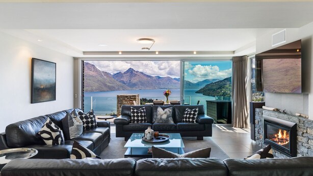 Een moderne woonkamer met een groot raam dat uitzicht biedt op een schilderachtig berg- en merengebied.