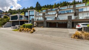 Een modern meerlaags huis met garage, grote ramen en oprit.