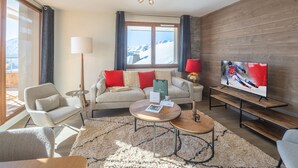 A modern living room with a sofa, armchairs, a coffee table, and a TV. - Lovely 6-person apartment, close to slopes, WiFi, pets allowed (Huez)