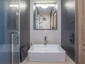 A modern bathroom with a rectangular sink, a glass shower enclosure, and a mirror above the sink.