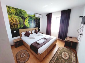A hotel room with a large bed, a wall-mounted air conditioner, a TV, and a wooden nightstand. - Paradiso Resort, in the heart of Danube Delta, 16 + 4 rooms for max. 55 persons (Sarinasuf)