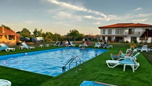 Una piscina con césped y sillas de descanso alrededor.