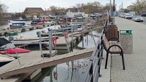Un puerto deportivo con barcos amarrados, un muelle de madera y un paseo pavimentado.