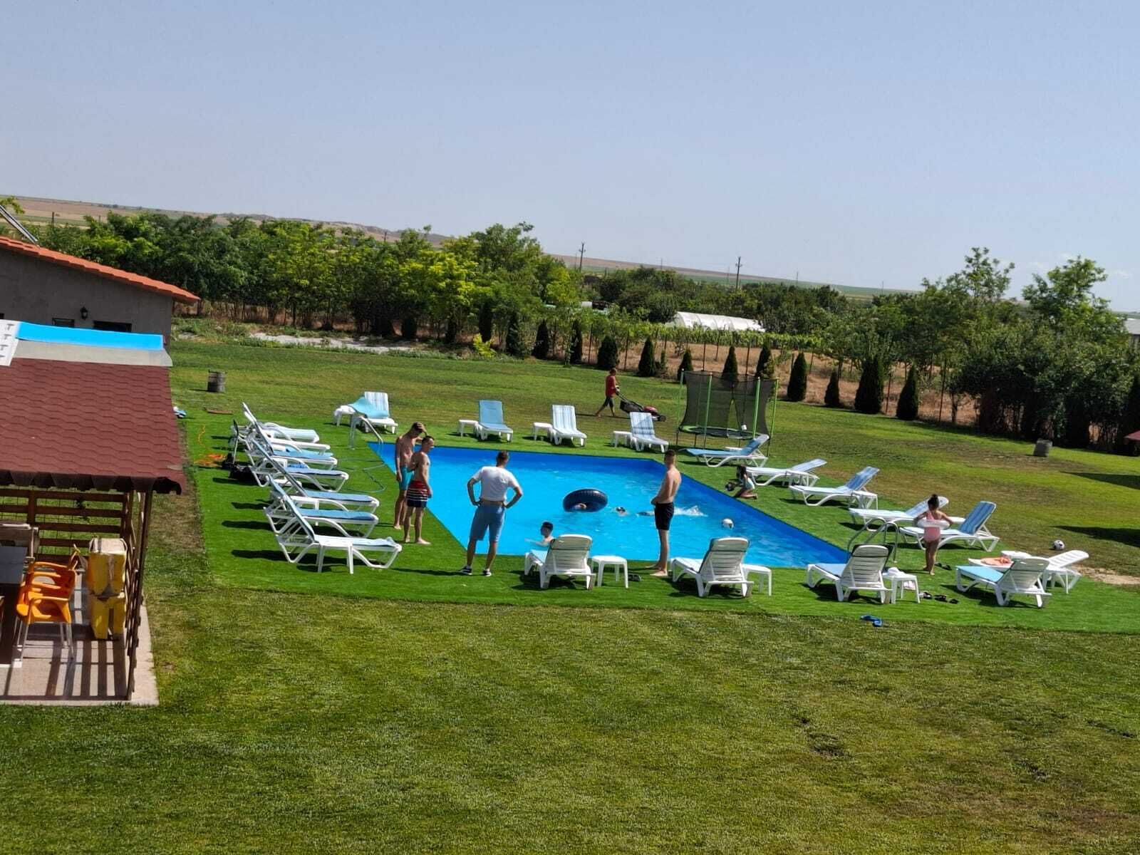 A swimming pool surrounded by white lounge chairs and a grassy area.