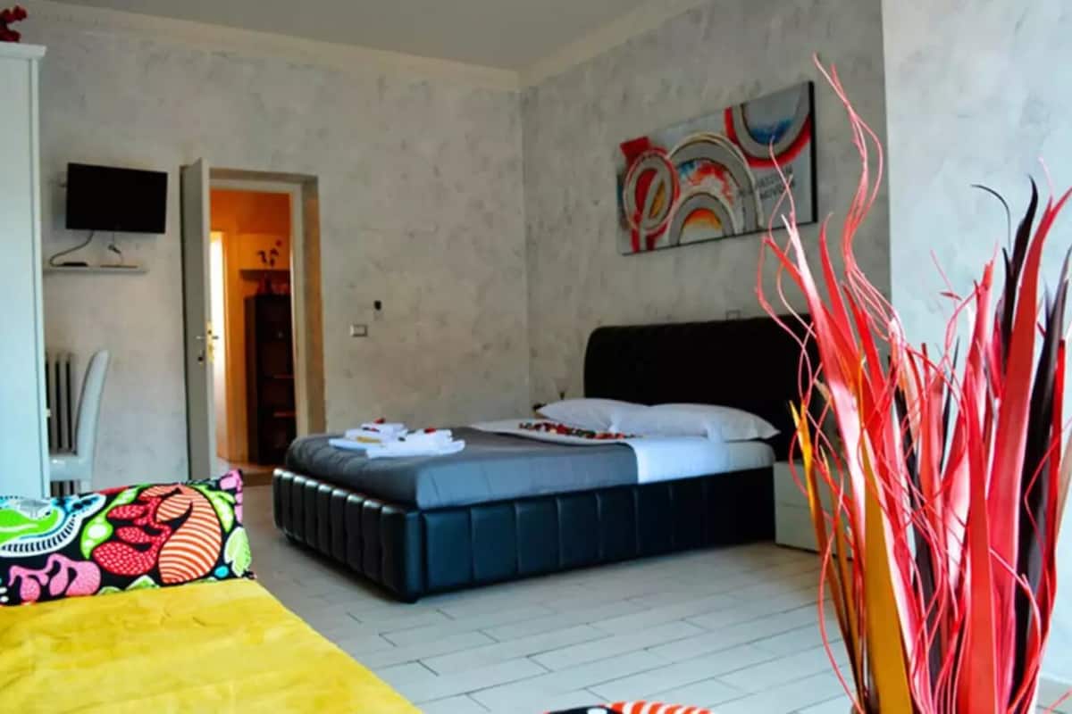 Un dormitorio con una cama, un televisor y un cuadro en la pared.