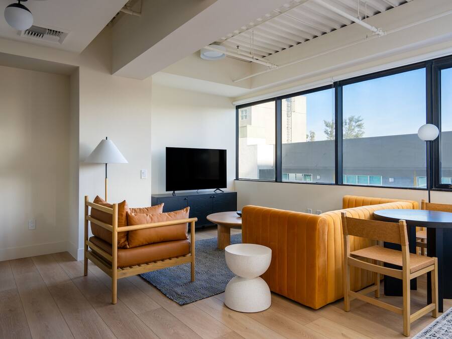 A modern living room with a sofa, a coffee table, a TV, and a dining table with chairs.