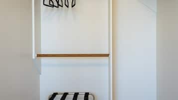 A room with a wooden floor, a white wall, and a metal bench with a black and white striped seat.