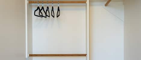 A room with a wooden floor, a white wall, and a metal bench with a black and white striped seat.