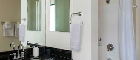 A bathroom with a double sink vanity, a large mirror, a shower with a glass door, and a towel rack.