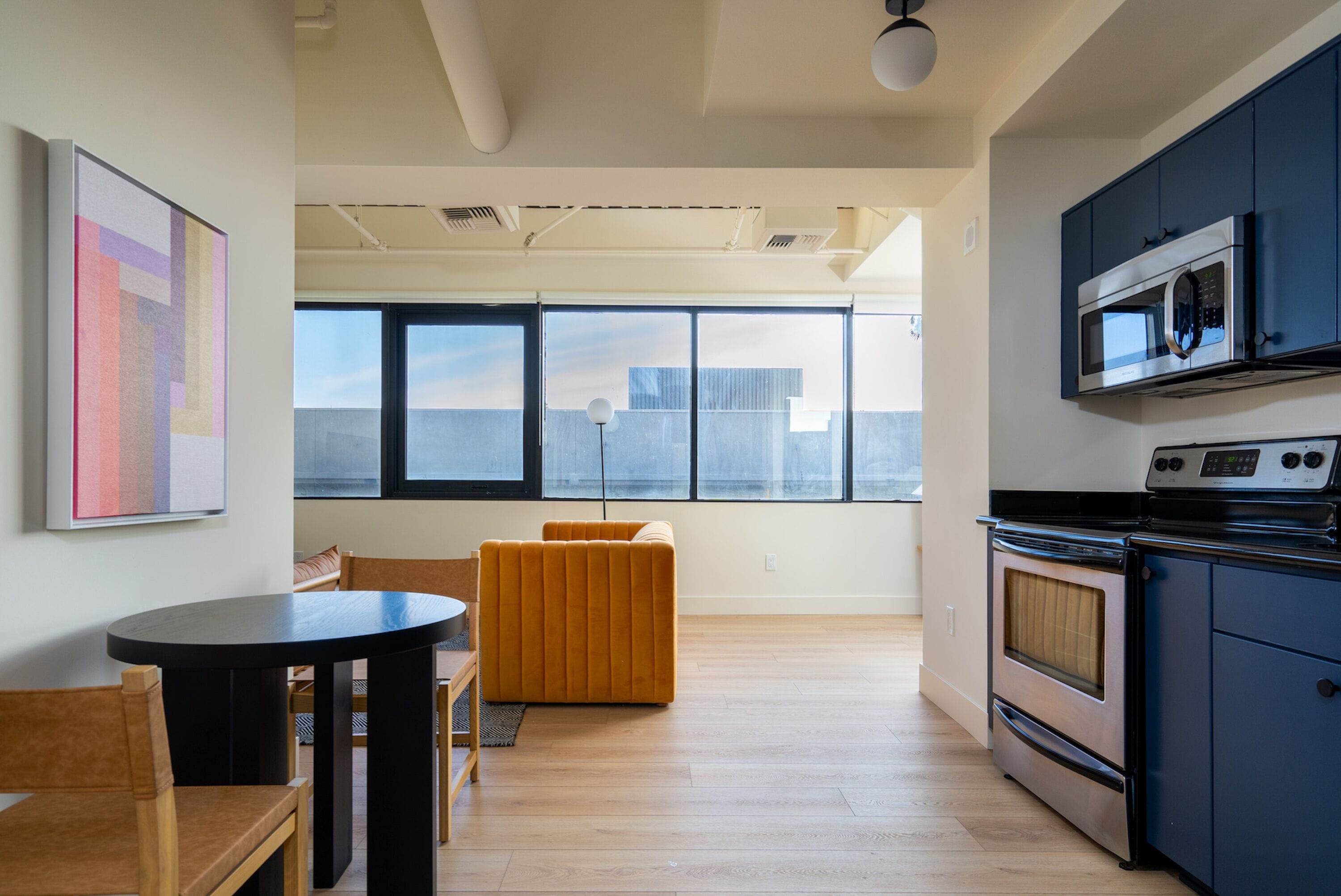 A modern kitchen with a large window, a dining area with a table and chairs, and a view of the city skyline.