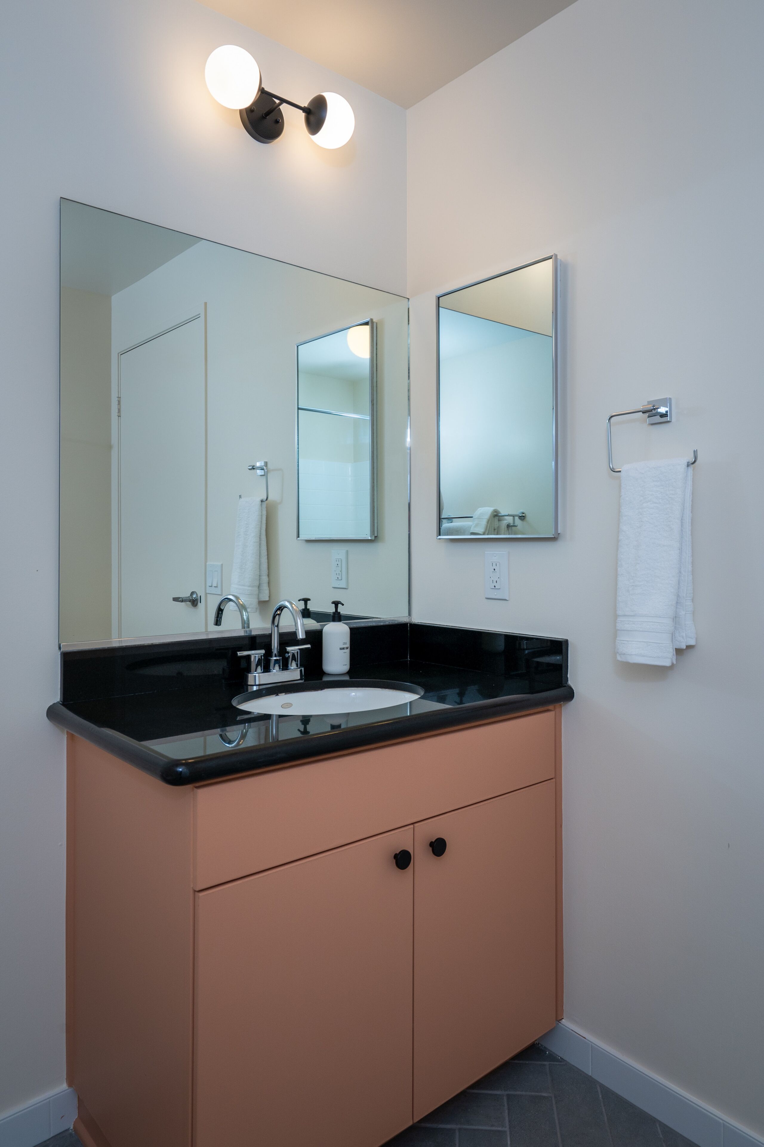 A bathroom with a black countertop sink, a large mirror, and a towel rack.