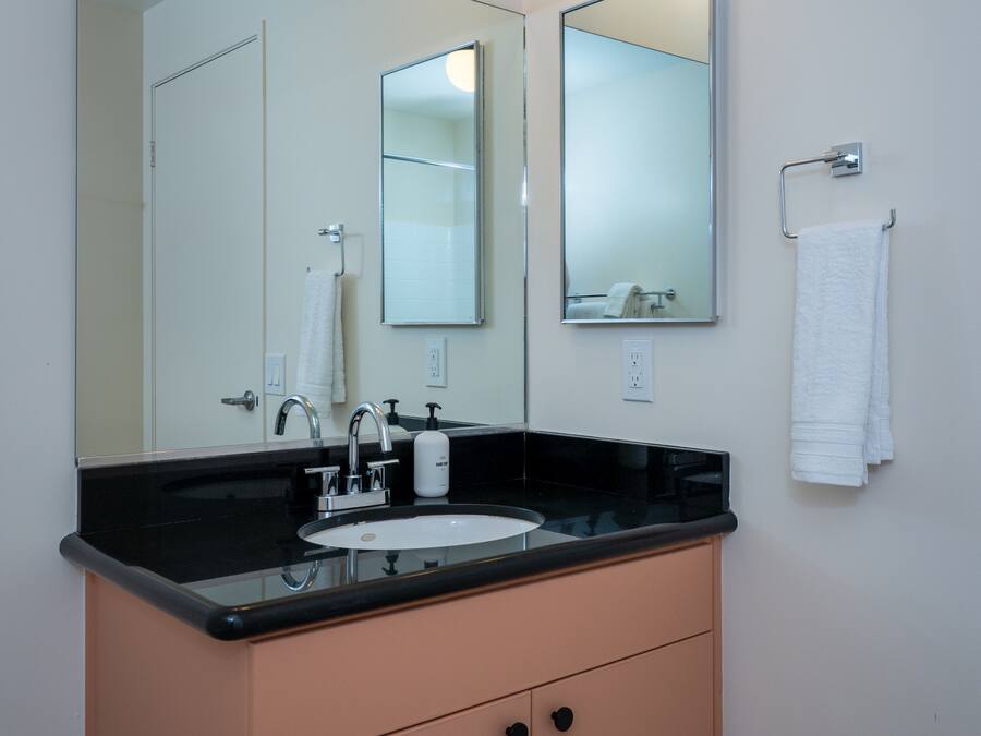A bathroom with a black countertop sink, a large mirror, and a towel rack.