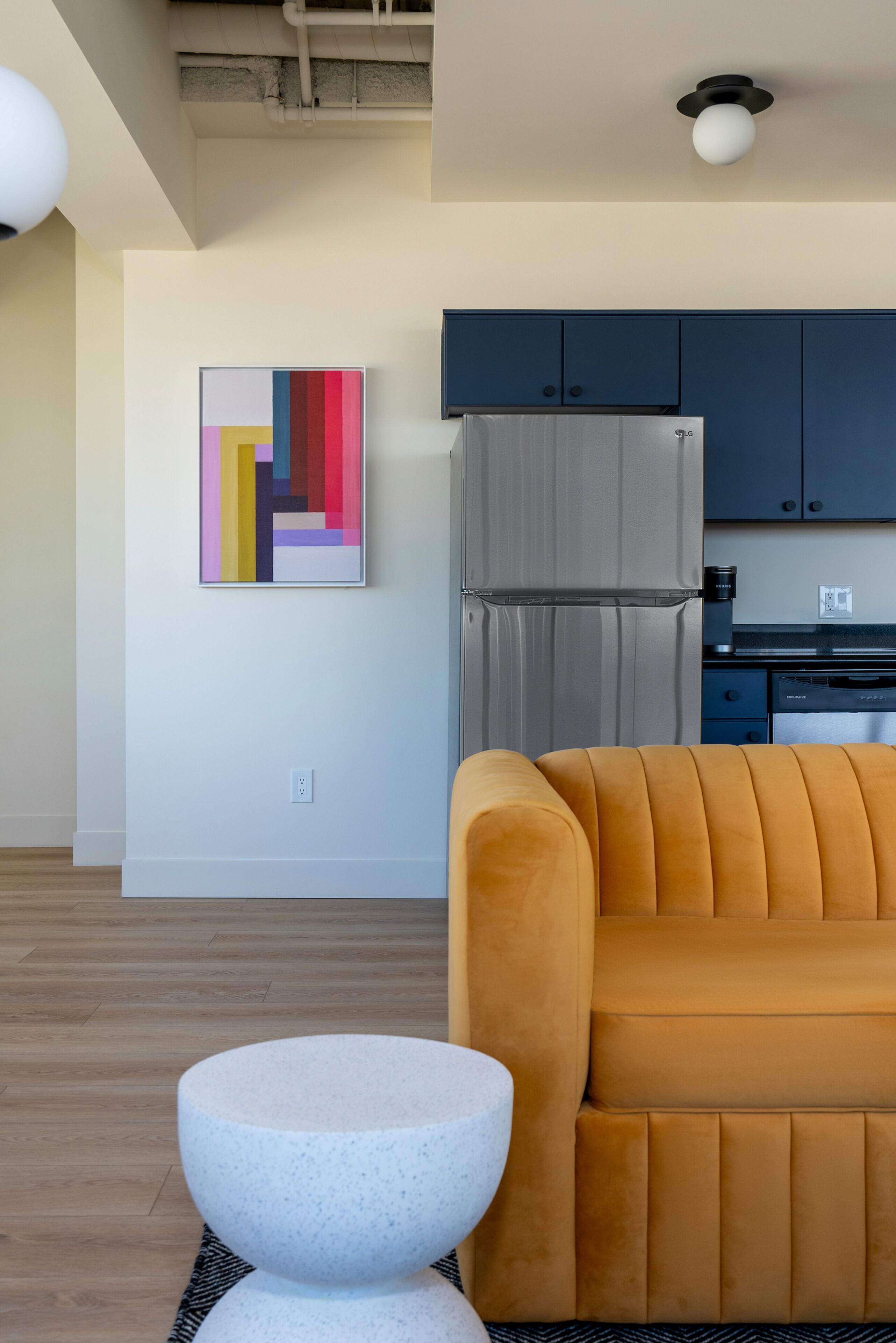 A modern living room with a sofa, a round table, and a kitchen in the background.