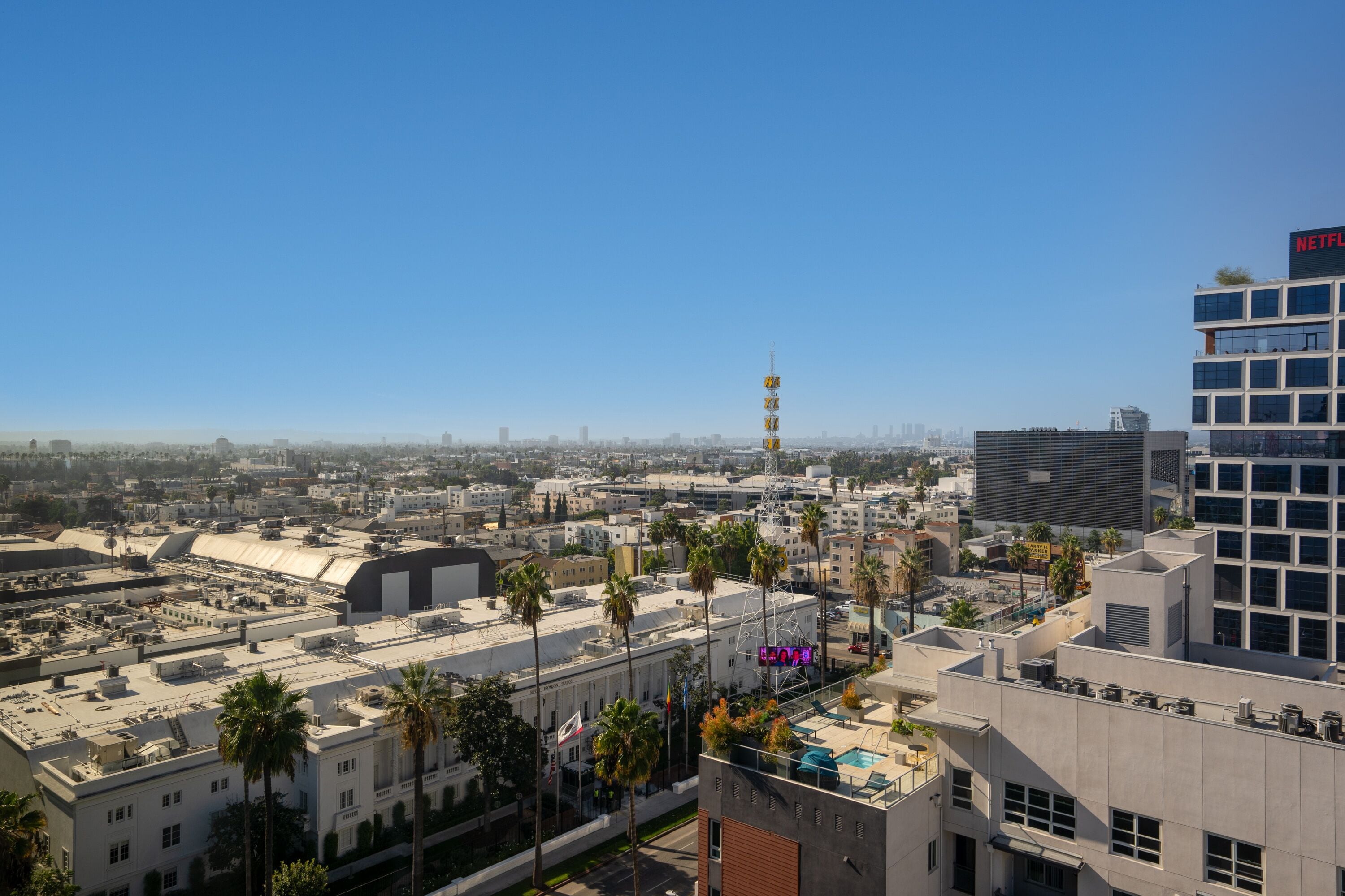 A high-rise building with a modern architectural design, featuring a prominent "NETFLIX" sign on the rooftop.