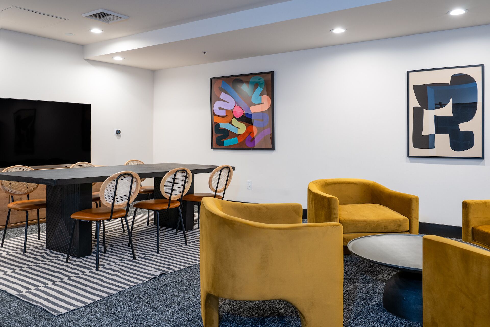 A modern conference room with a large table, chairs, and a television.