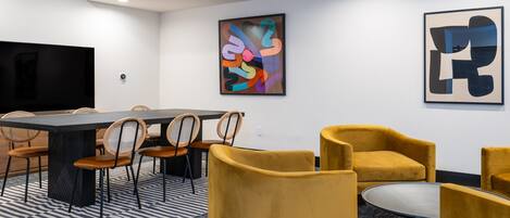 A modern conference room with a large table, chairs, and a television.