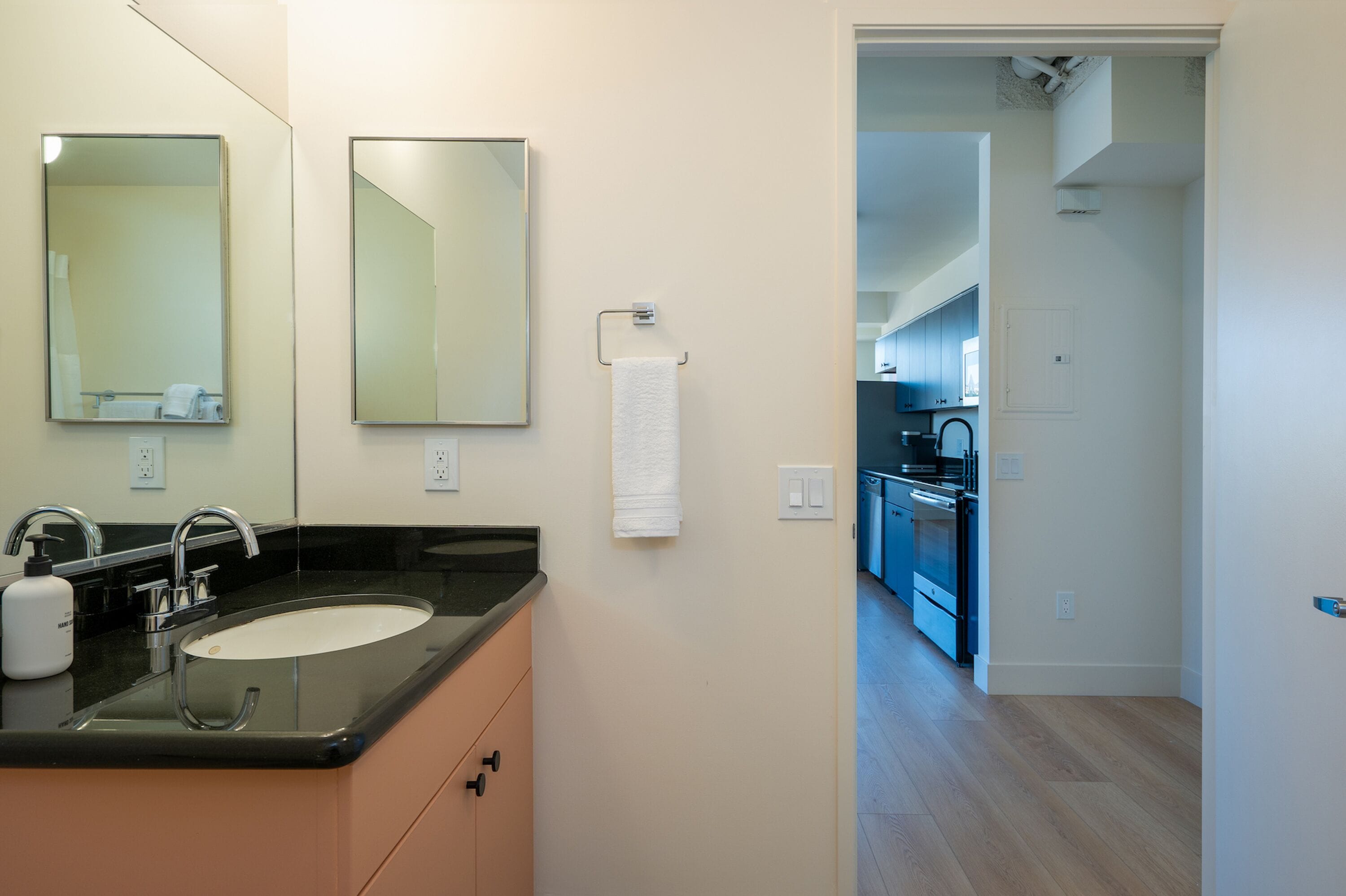 Une salle de bain moderne avec un lavabo, des miroirs et une serviette accrochée au mur.