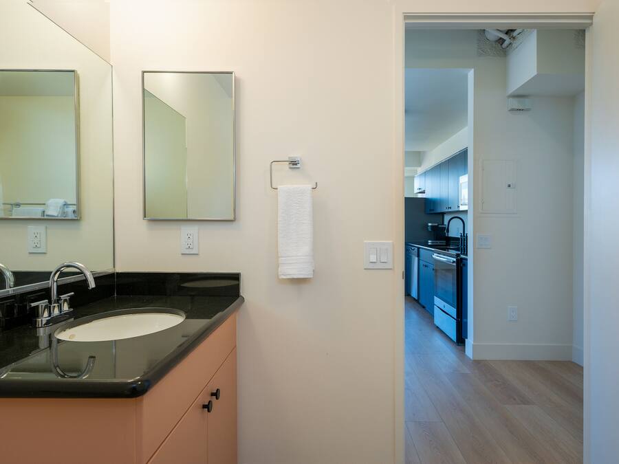 Un bagno moderno con un lavandino, specchi e un asciugamano appeso al muro.