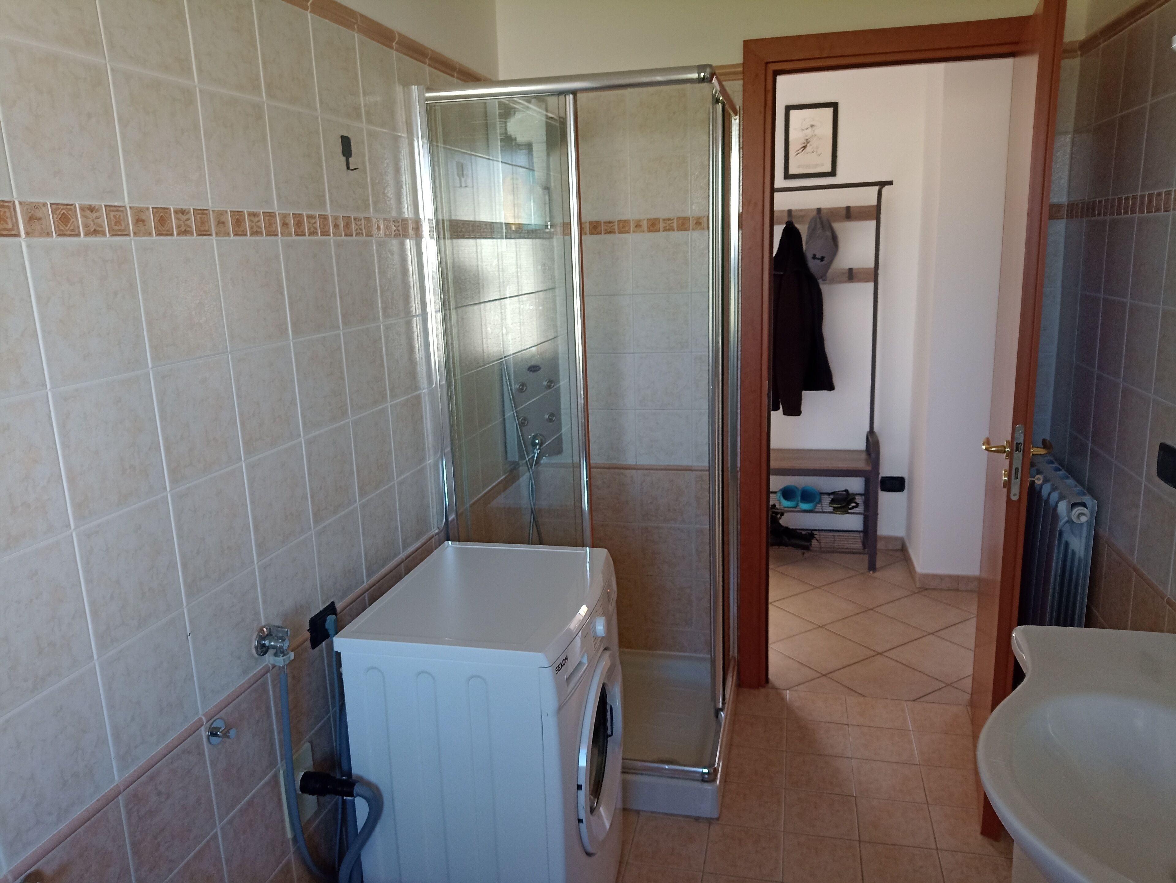 Un baño con ducha de cristal, lavadora y radiador.