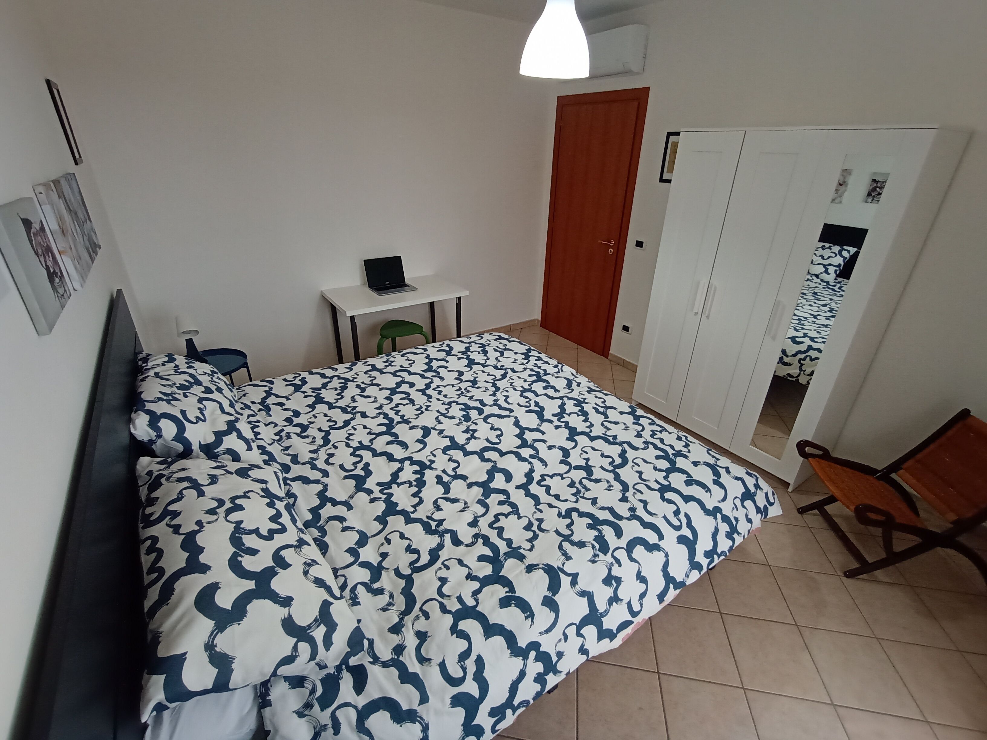 Une chambre à coucher avec un lit, un bureau avec un ordinateur portable, une armoire et une chaise.