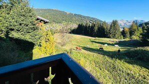 A scenic view of a mountainous area with a wooden cabin and grazing horses. - Family chalet near slopes with WiFi and parking (Les Gets)