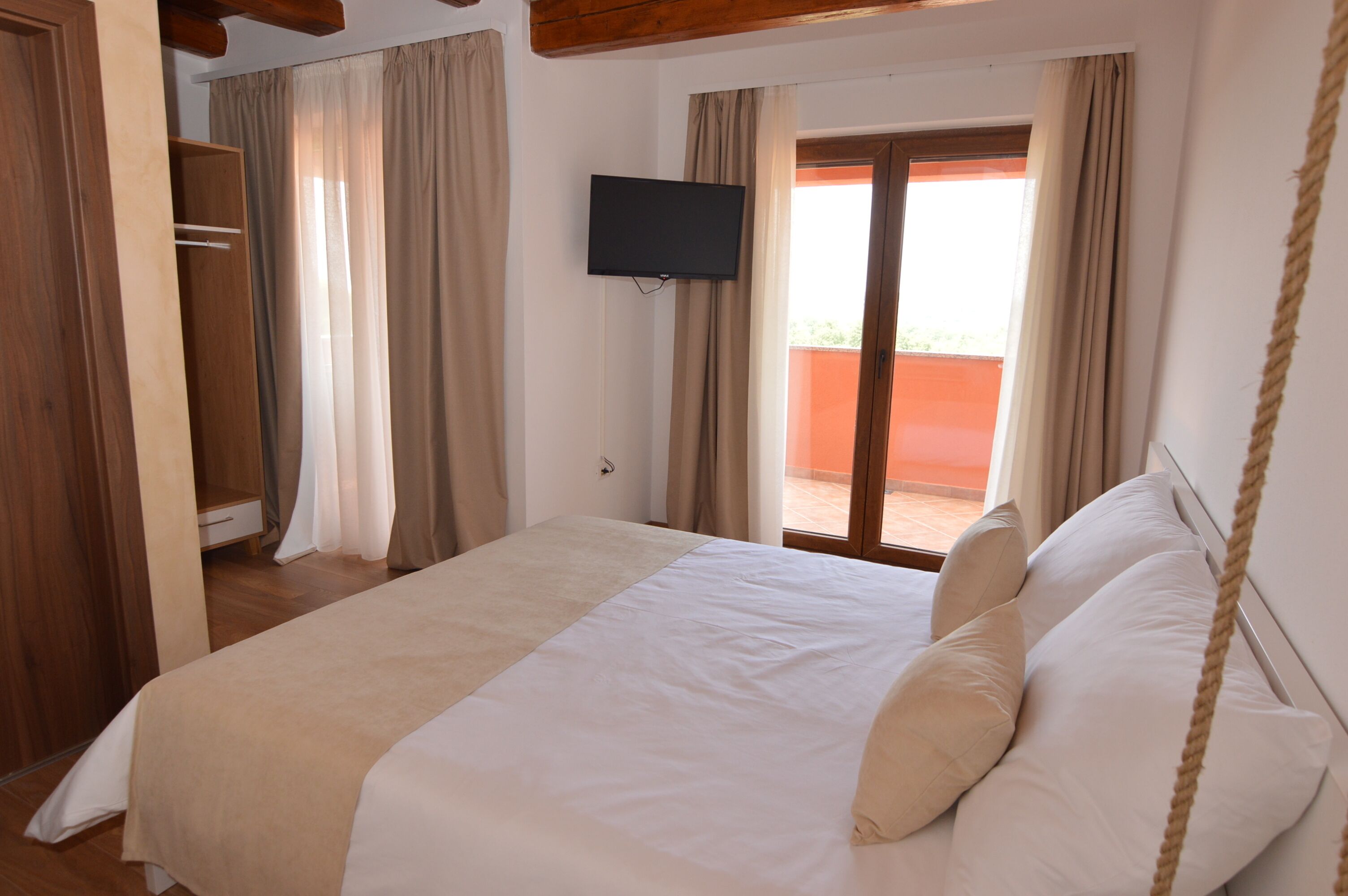Une chambre à coucher avec un lit, une télévision, une armoire et une vue sur l’extérieur.