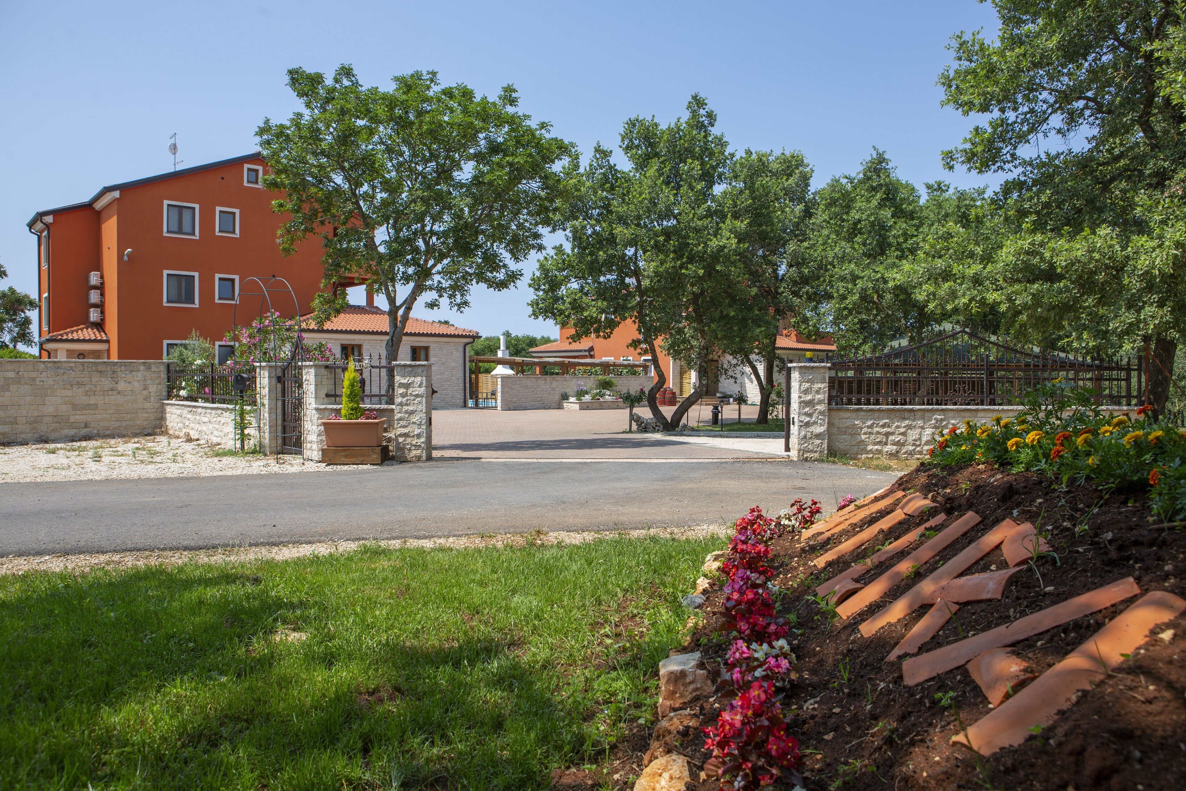 Un quartier résidentiel avec un bâtiment rouge, une route pavée et un espace verdoyant agrémenté de parterres de fleurs.
