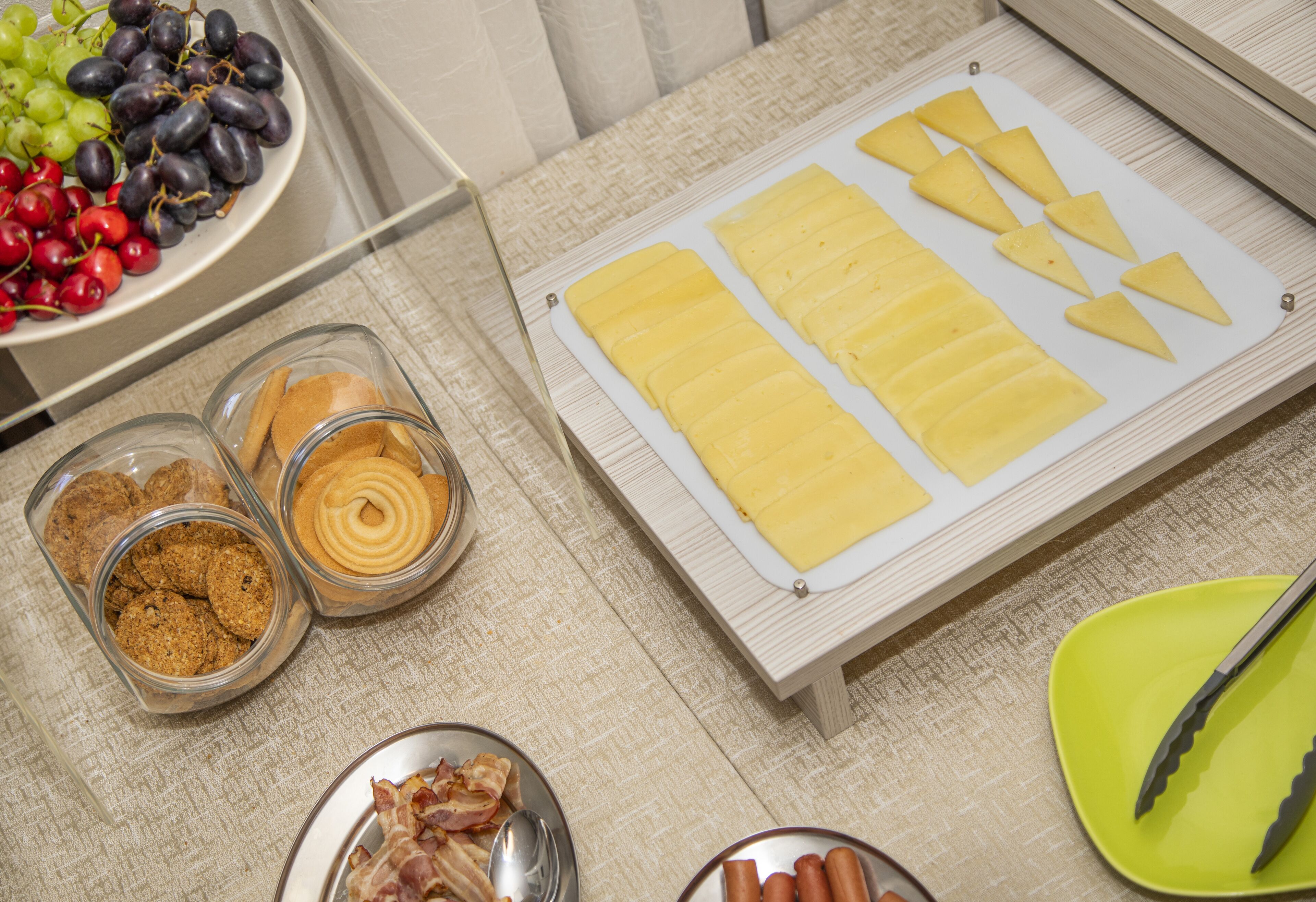 A buffet table with various food items including grapes, cherries, pineapple slices, and meat.