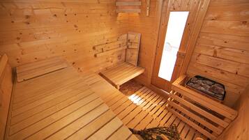 Eine Holzsauna mit Bänken, einem Fenster und einer Ablage für Steine.