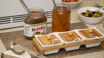 Un plan de travail de cuisine avec un pot de Nutella, un pot de miel et une planche à découper en bois, sur laquelle repose une cuillère.