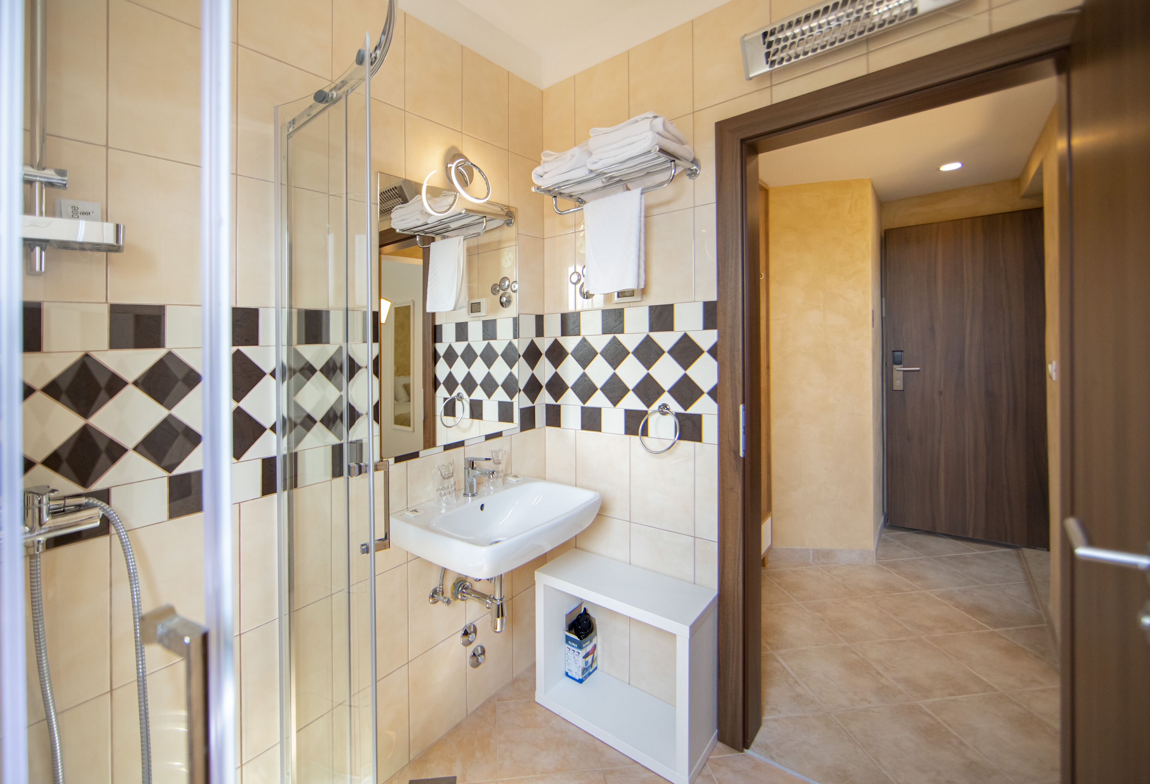 A modern bathroom with a glass shower enclosure, a white sink, and a tiled backsplash.