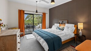 Une chambre d’hôtel équipée d’un lit, d’un bureau, d’une chaise, d’une lampe, d’un ventilateur de plafond et offrant une vue sur l’extérieur grâce à une porte coulissante.