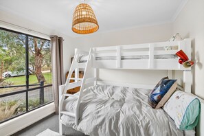 A bunk bed with a ladder, a window with curtains, and a hanging light fixture. - Blue Haven at Aireys (Aireys Inlet)