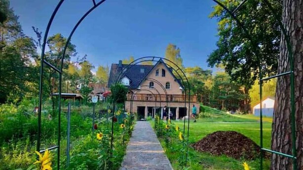 Ein gepflasterter Weg führt zu einem Haus mit einem geneigten Dach und einem Balkon.