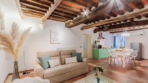 A cozy living room with a beige sofa, a glass coffee table, and a dining area with a white table and chairs. - Casa Al Dipinto in Lucca (Lucca)