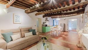 A spacious living room with a high wooden ceiling, a green kitchen island, and a dining area with white chairs. - Casa Al Dipinto in Lucca (Lucca)