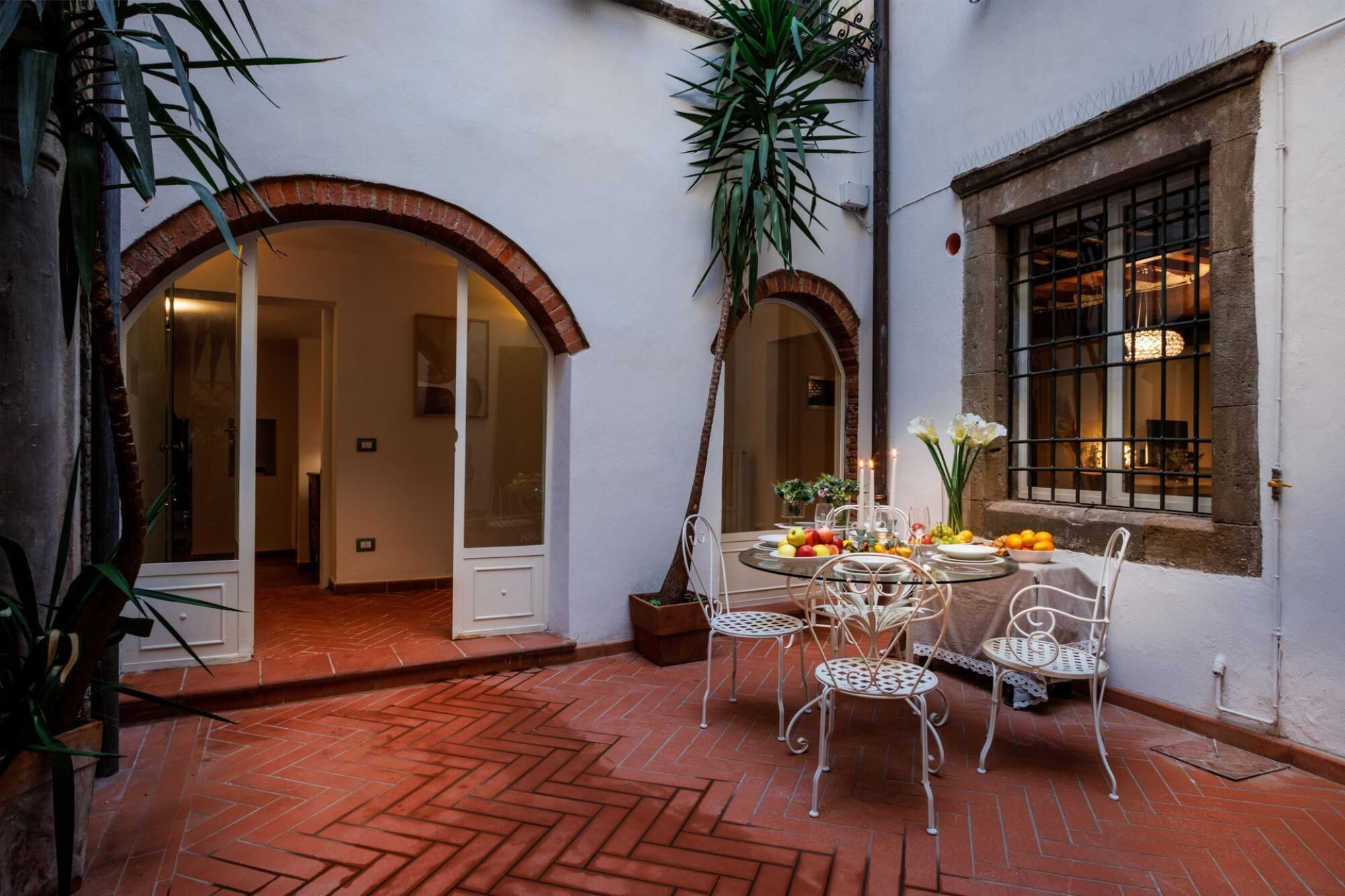An outdoor dining area with a round table, four chairs, and a potted plant.