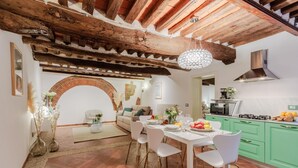 A dining area with a brick archway, white dining table, and chairs. - Casa Al Dipinto in Lucca (Lucca)